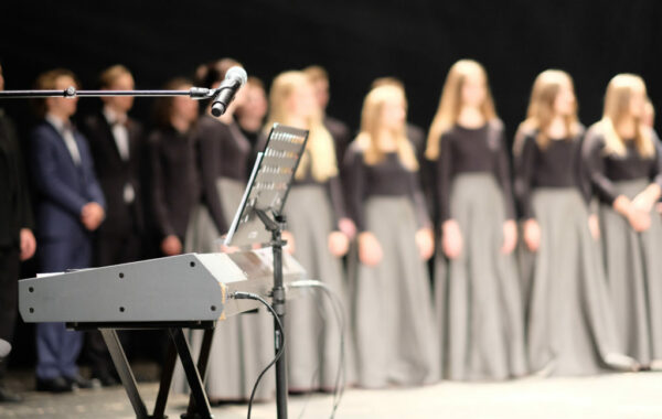 Microphone and music stand in front of electric pianos on the stage of the theater